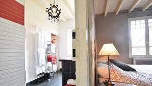 Et hotelværelse med en seng, et natbord, en lampe, et vindue og et badeværelse i baggrunden.