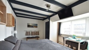 A bedroom with a bed, a desk, and a window. - Elegant studio near beach (Bergen aan Zee)
