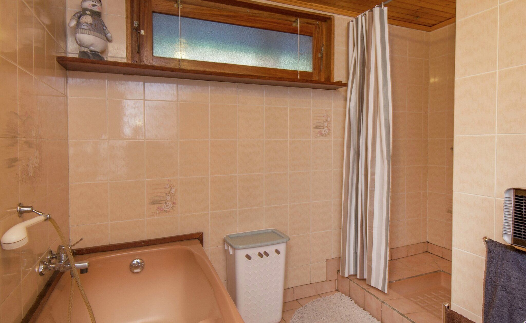 A bathroom with a bathtub, shower, and a window above the sink.