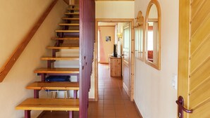 Un escalier en bois mène à un couloir où se trouvent une porte en bois et un miroir.