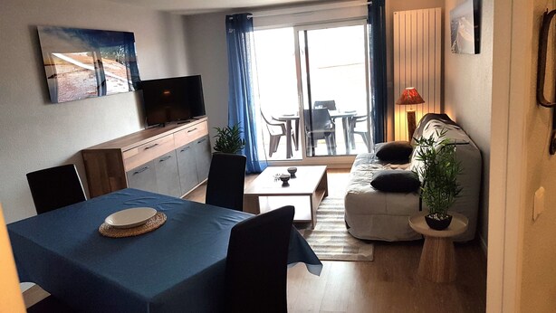 Ett kompakt vardagsrum med ett matbord, en soffa och en tv som står på ett skåp.