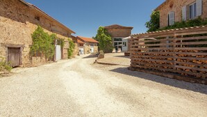 A narrow gravel road flanked by stone buildings with wooden fences and a clear blue sky. - Holiday Home in Saint-Léonard with Pool (Saint Léonard de Noblat)