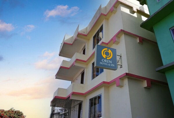A hotel named OREN HOTEL & SPA with a modern architectural design, featuring balconies and a clear sky in the background.