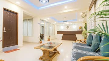 Uma sala de estar moderna com um sofá, uma mesa de centro, uma cadeira de madeira e uma mesa de recepção.