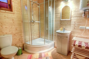 A wooden interior with a glass-enclosed shower, a toilet, a sink, and a towel rack.