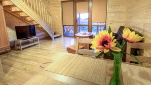 A wooden interior with a TV on a stand, a dining table with a vase of flowers, and a staircase. - Holiday home located near the sea; ideal for relaxing with family. (Mielno)