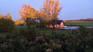Ein ländliches Haus mit Teich, umgeben von Bäumen und viel Grün.