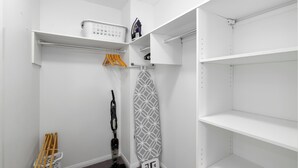 A neatly organized closet with shelves, hanging space, and a vacuum cleaner. - Water Views with a Splash of Luxury (BONGAREE)