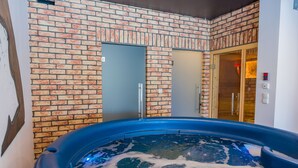 Et spaområde med jacuzzi, murstensvægge og en trädør.