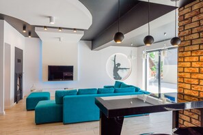Una sala de estar moderna con un sofá seccional color turquesa, una mesa de centro negra e iluminación colgante.