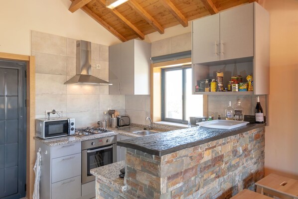 A modern kitchen with a stone island, stainless steel appliances, and a window providing natural light. - Holiday home with private pool (Valença-de-Douro)