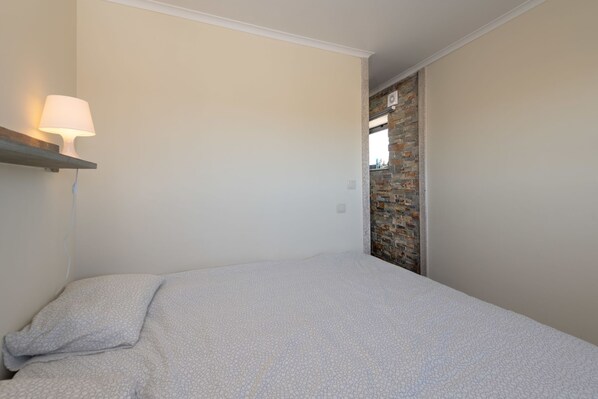 A bedroom with a bed, a nightstand, a wall-mounted lamp, and a brick wall. - Holiday home with private pool (Valença-de-Douro)