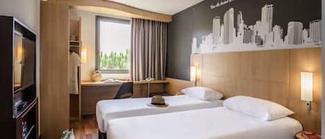 Habitación de hotel con dos camas, un escritorio, un televisor y un mural con vistas a la ciudad.