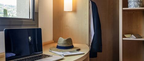 Een moderne kamer met een houten bureau, een laptop, een hoed en een jas hangend aan de muur.