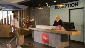 A reception area with a wooden reception desk, a computer, and a sign that reads "RECEPTION". - Hôtel Ibis Cannes Mouans Sartoux (Mouans-Sartoux)