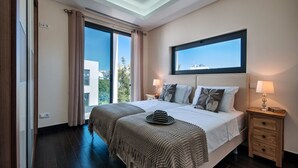 A modern bedroom with a large bed, two bedside tables, a skylight, and a view of the outdoors.
