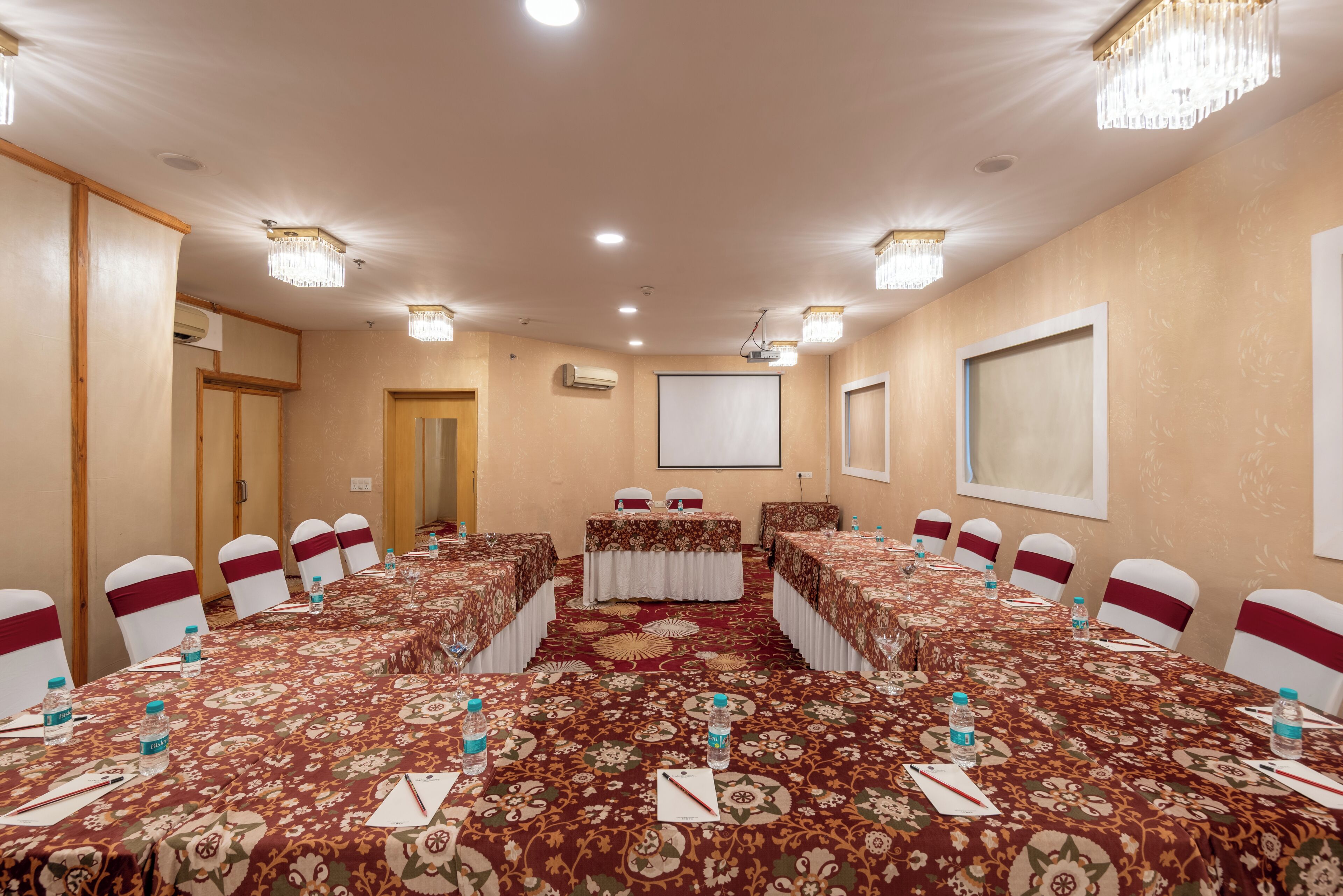 A conference room with a long table, chairs, and a projector screen.