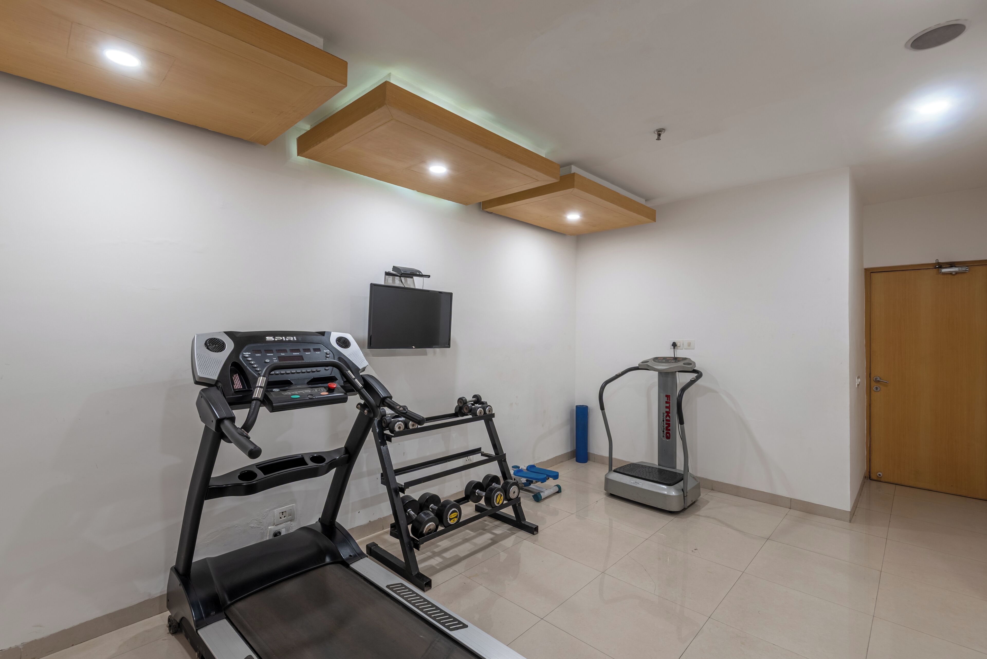 A home gym with a treadmill, elliptical, and dumbbells.