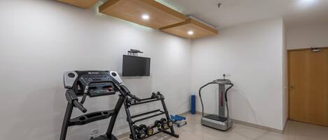 A home gym with a treadmill, elliptical, and dumbbells.