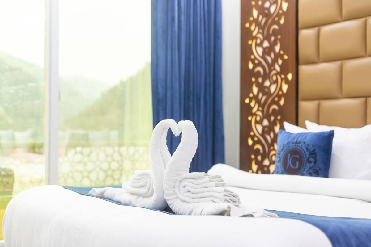 A hotel room with a bed, a blue curtain, and a decorative wall panel.