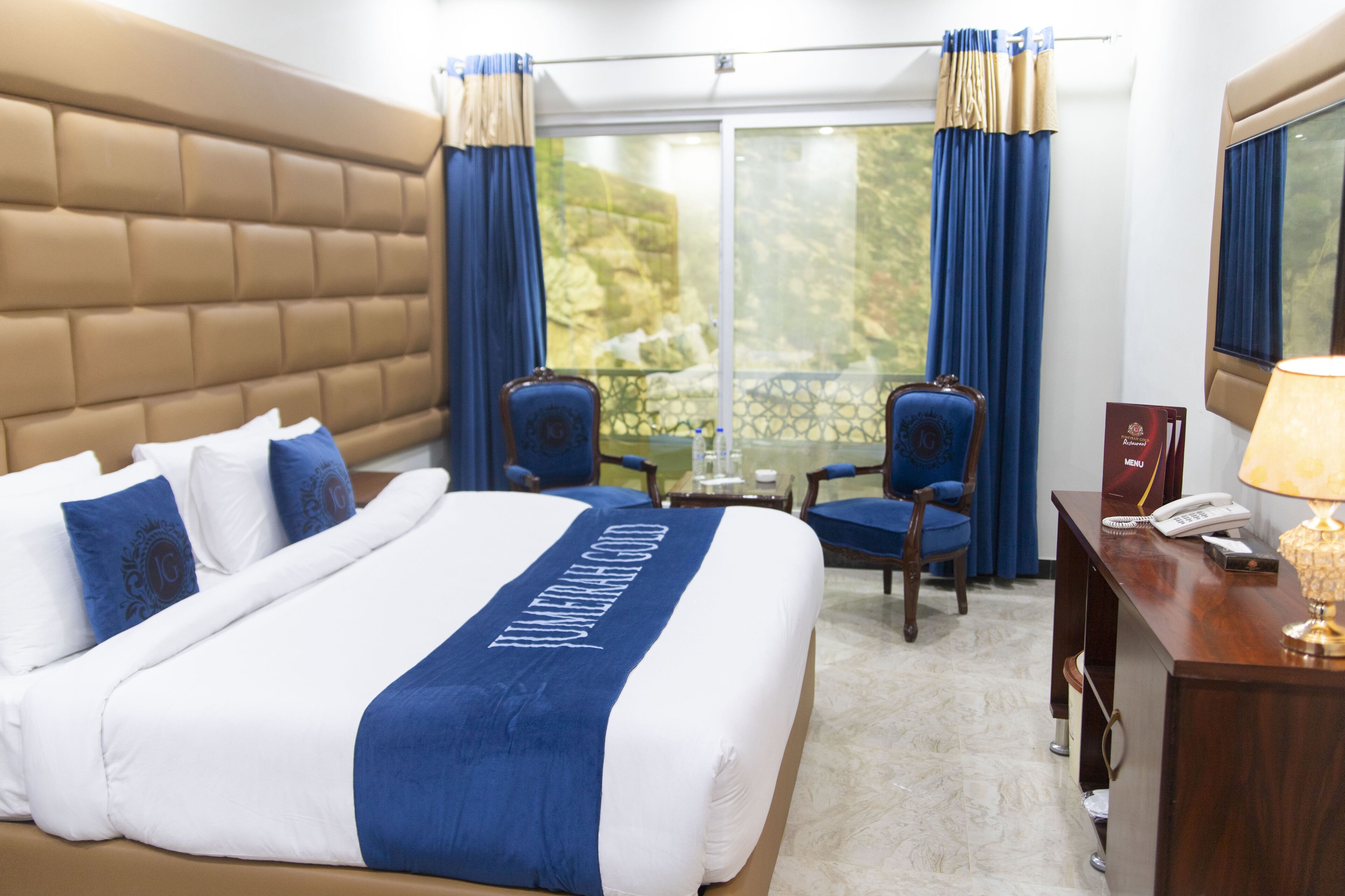 Habitación de hotel con una cama grande, un escritorio con teléfono y vistas al exterior a través de un ventanal.