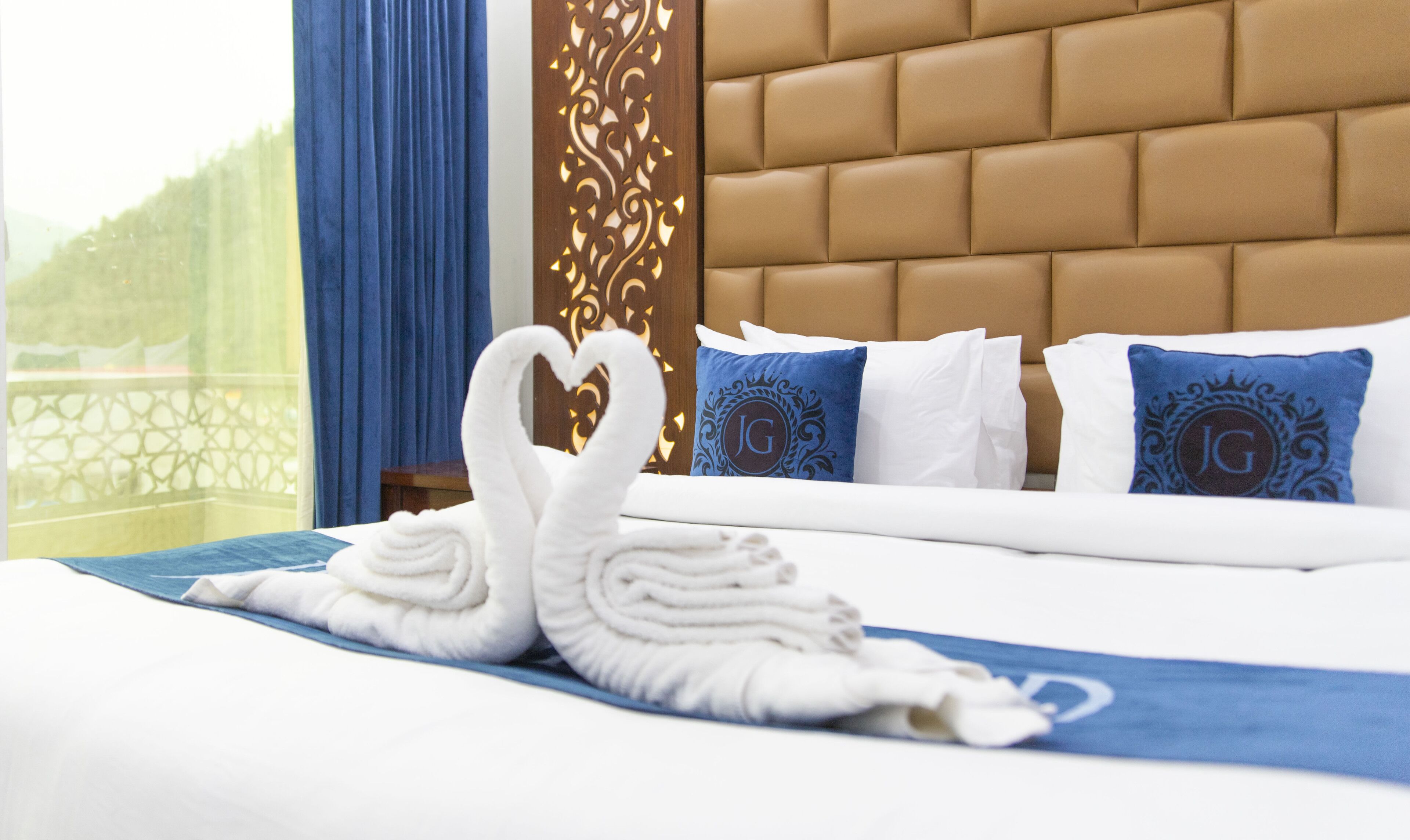 Ein Hotelzimmer mit Bett, einer Zierleiste an der Wand und Blick durch ein Fenster.