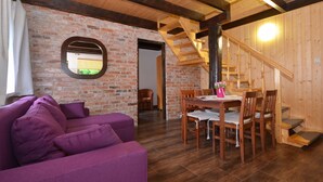 Ein gemütliches Zimmer mit einem violetten Sofa, einem Holzespeisetisch und einer Backsteinwand.