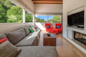 A modern living room with a sofa, two red armchairs, a coffee table, and a TV.