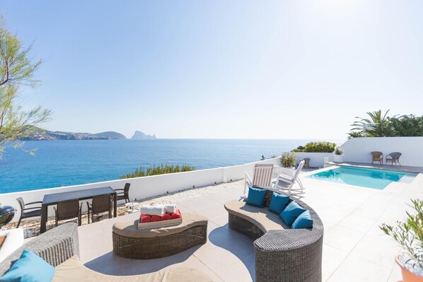 A rooftop terrace with a pool, outdoor seating, and a view of the sea.