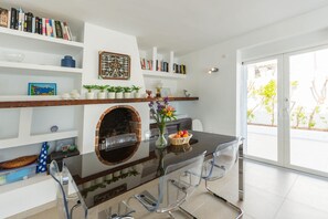 A modern kitchen with a central island, a built-in oven, and a dining area with clear chairs.