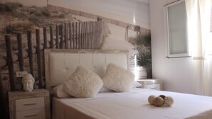 Une chambre à coucher comprenant un lit, deux tables de chevet, une sculpture représentant une tête de Bouddha et une fresque murale sur le thème du désert.