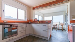 A modern kitchen with white cabinets, a Bosch oven, and a red countertop. - Modern Villa near Beaches (Roses)