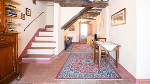 Eine Treppe mit Holzwerteln, ein Essbereich mit Tisch und Stühlen sowie ein Teppich mit Muster auf dem Boden.