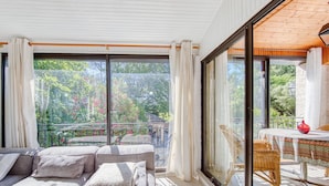Een balkon met een bank en tafel, grote ramen en uitzicht op groen.