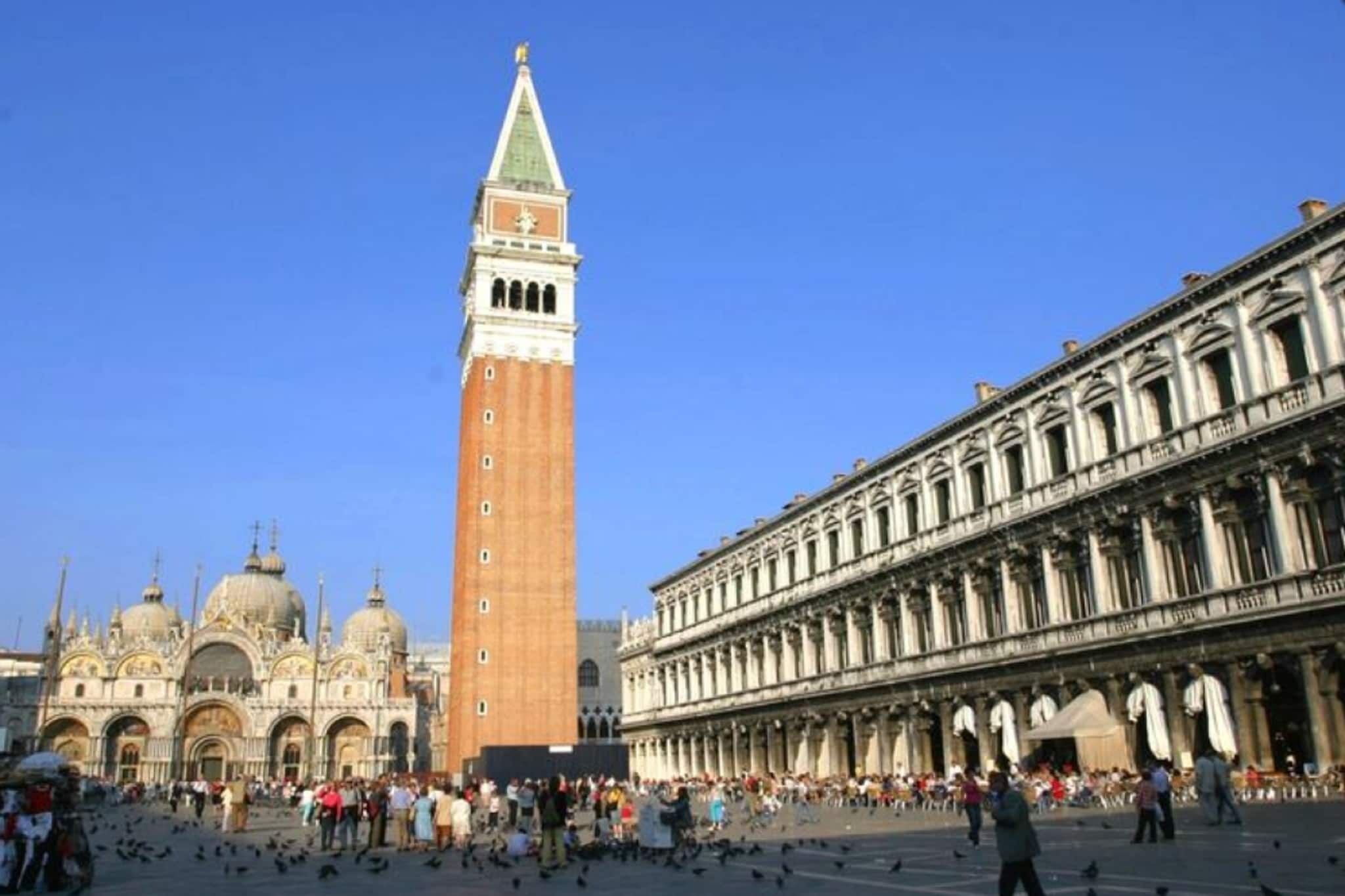 Una piazza storica con una torre imponente e un grande edificio dall'architettura classica.