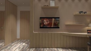 Una habitación moderna con pared de paneles de madera, televisor de pantalla plana montado y un escritorio con silla.