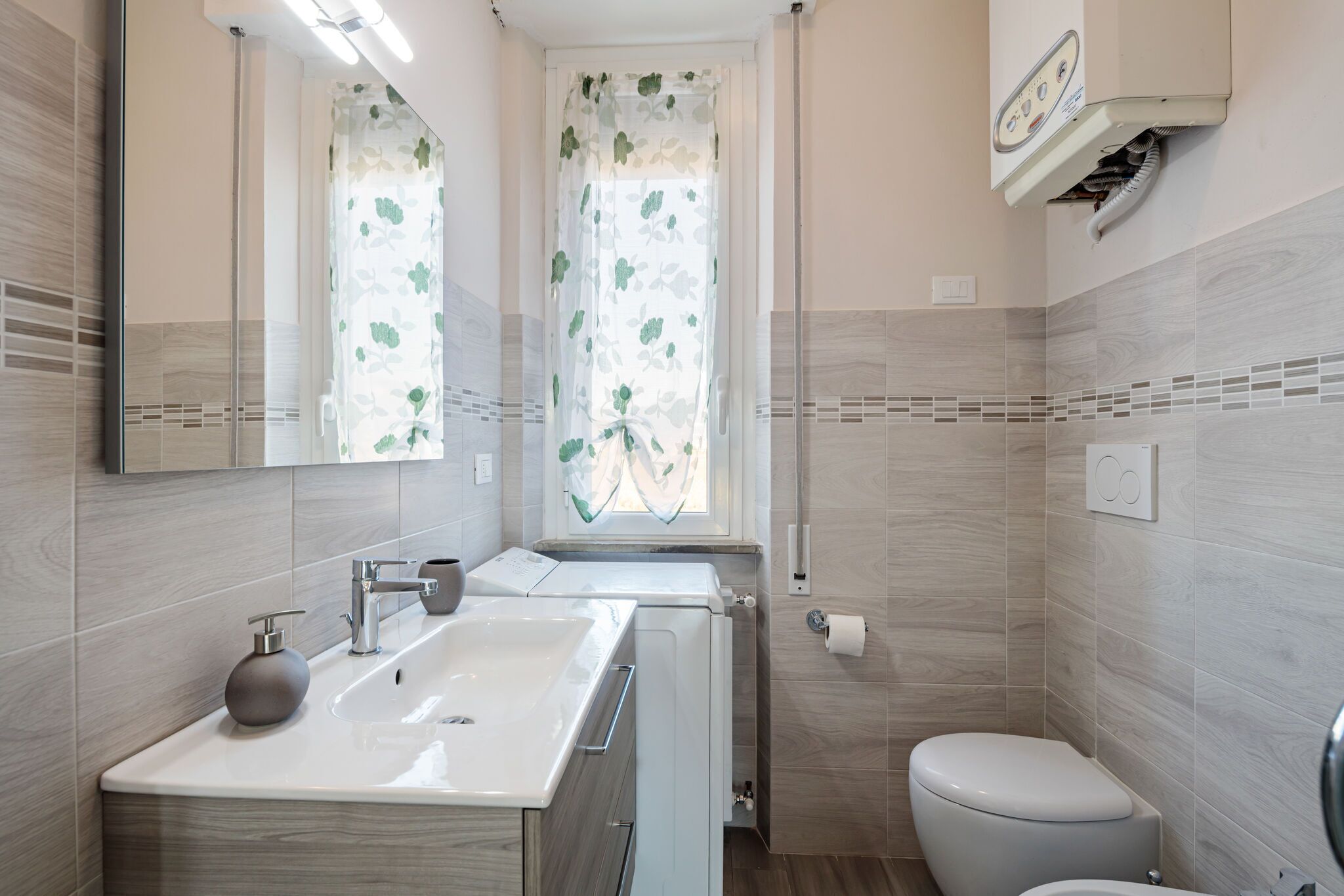 A modern bathroom with a sink, mirror, toilet, and shower.