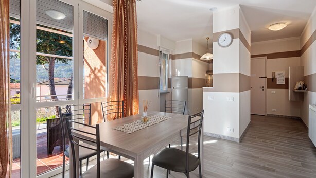 A modern kitchen with a dining area, large windows, and a view of the outdoors.
