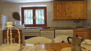 Cozinha com armários de madeira, fogão, lava-louças e uma cafeteira sobre a mesa.