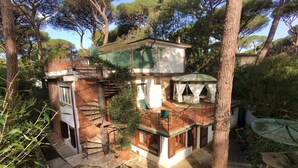 Uma casa de dois andares com varanda, escadaria e um pequeno jardim.