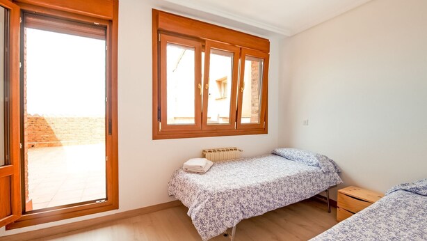 Ein Schlafzimmer mit einem Einzelbett, einem kleinen Nachttisch, einem Heizkörper und einem Fenster mit Holzrahmen.