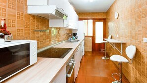 Une cuisine équipée d’un four à micro-ondes, d’une cuisinière et d’un évier. On y trouve une chaise et une table dans un coin.
