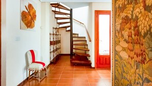 Un escalier menant à un deuxième étage, une chaise avec un coussin rouge et un mur orné de motifs.