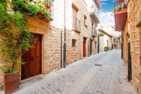 A narrow cobblestone street flanked by stone buildings with wooden doors and balconies. - Belvilla by OYO Casa rural (laguardia)