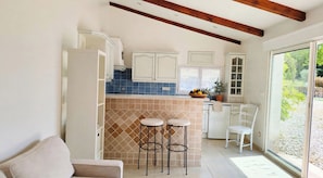 A compact kitchen with a built-in bar area, a dining chair, and a view of the outdoors.