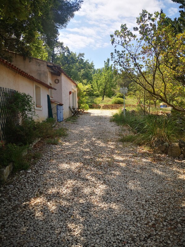 A gravel path leading to a rustic building with a tiled roof and a door.