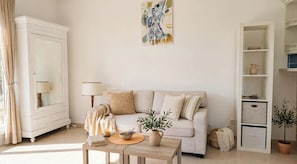 A living room with a sofa, a coffee table, a lamp, a painting, and a cabinet.