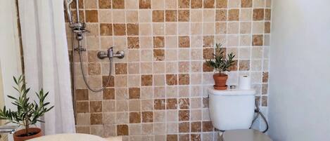 A bathroom with a shower, toilet, sink, and a window.