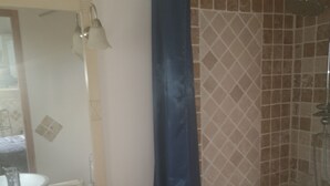 Un baño con lavabo, espejo y zona de ducha.