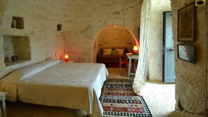 A rustic room with a bed, a small table, a sofa, and a patterned rug.